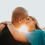 man in blue shirt kissing woman in black shirt