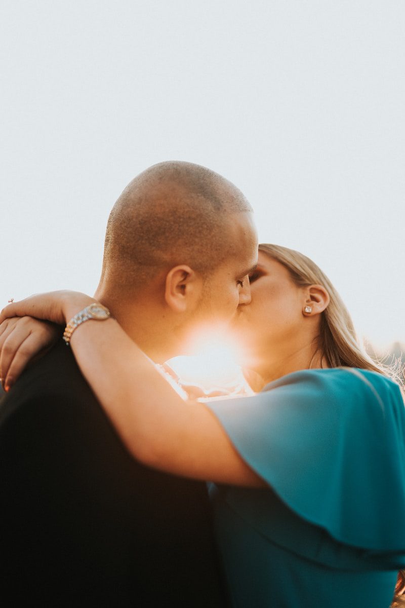 man in blue shirt kissing woman in black shirt